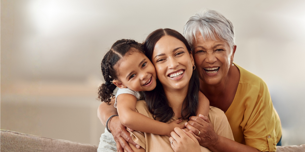 A supportive family with a grandmother, mother, and young daughter, all smiling.